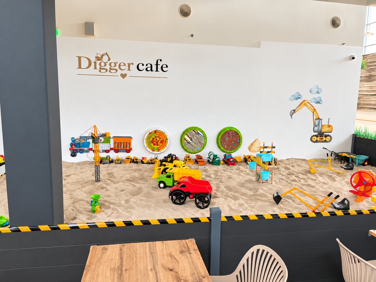 Vnitřní pískoviště Digger cafe s barevnými tatrovkami a hračkami na stěně